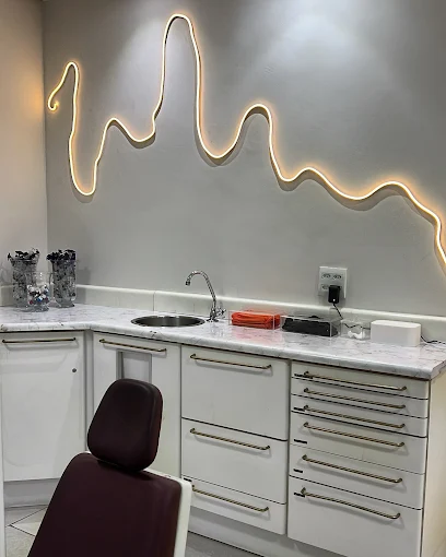 Consultório da clínica com cadeira odontológica e iluminação decorativa